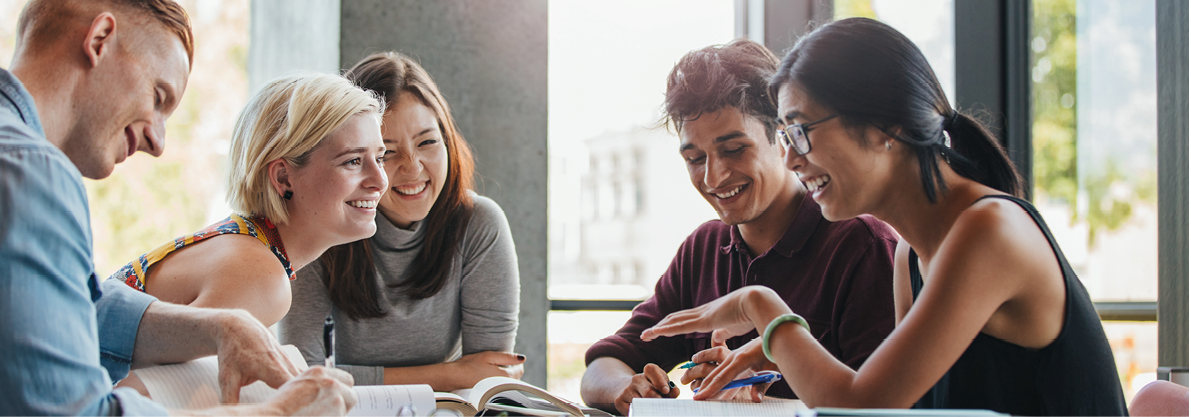 Happy young university students studying with books in library. Group of multiracial people in college library.